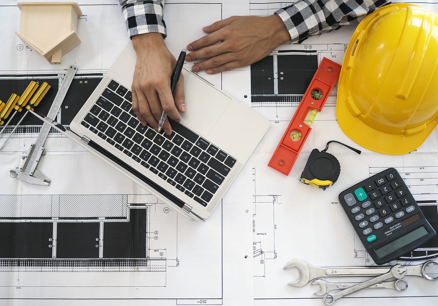 Engineers Work With Laptops And Blueprints. Calculate And Check Engineers work with laptops and blueprints. Calculate and check the construction project.