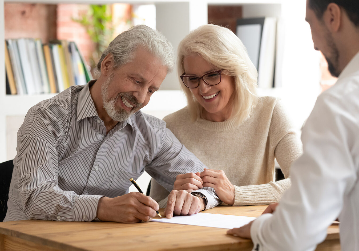 Happy older couple clients sign insurance contract meeting agent