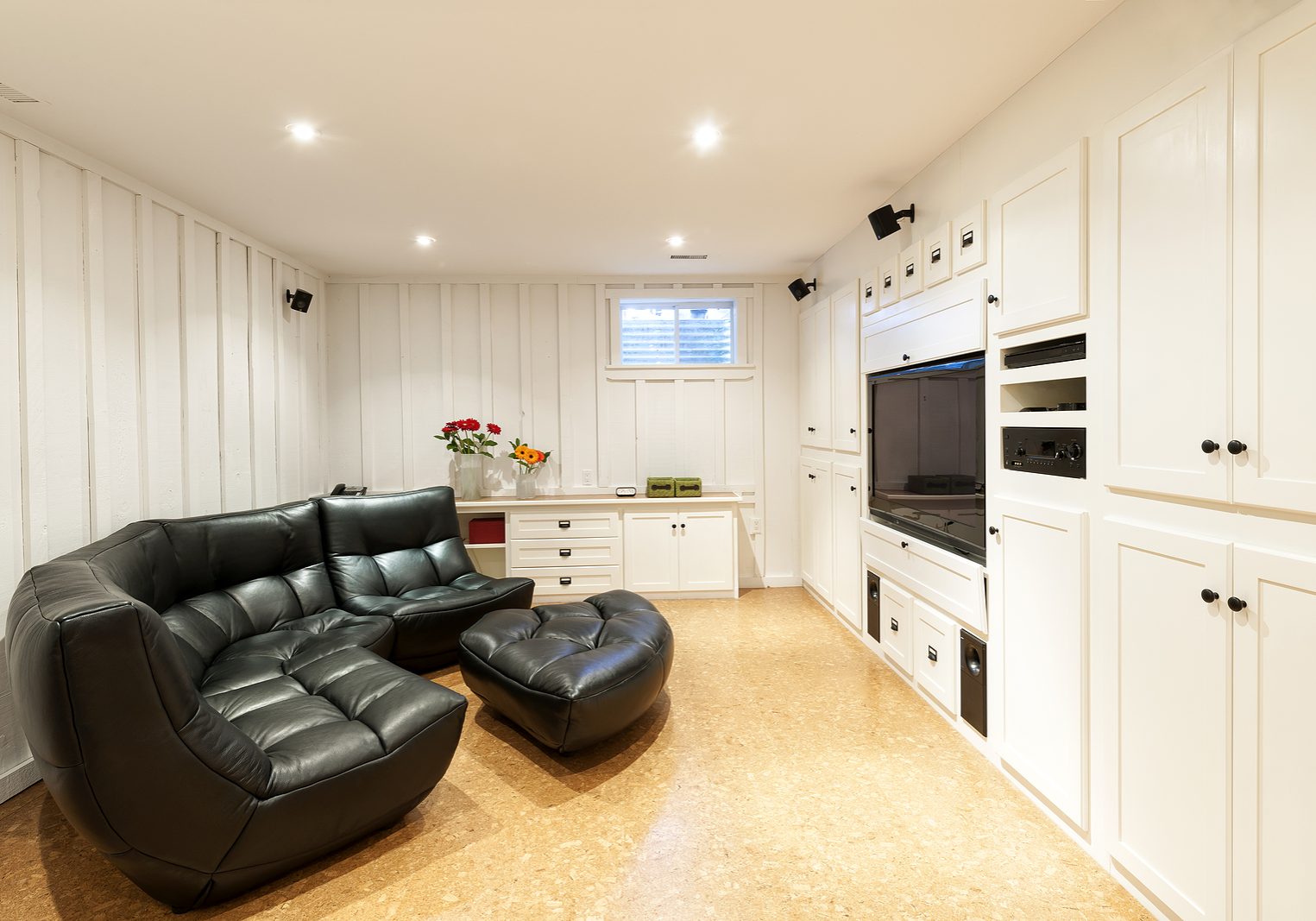 Finished basement of residential home with entertainment center couch and television.