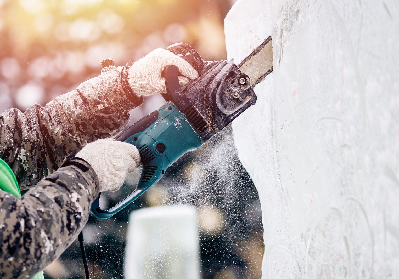 Ice sculpture carving man use chainsaw cut frozen winter