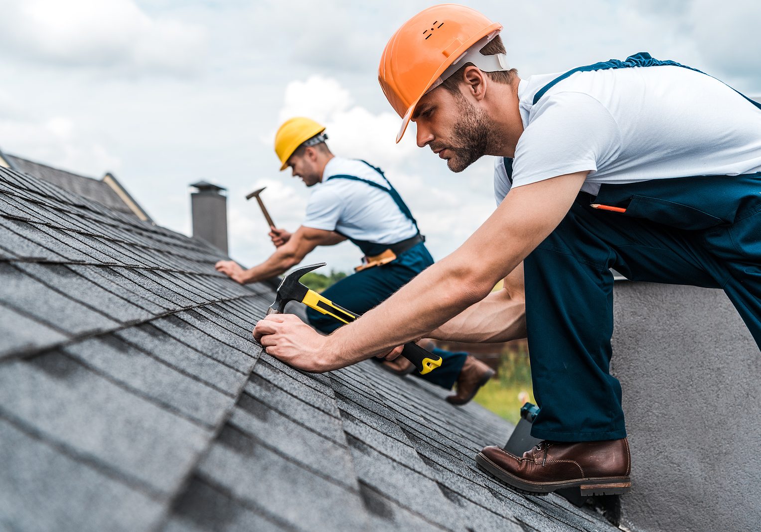 Selective Focus Of Handsome Handyman Repairing Roof With Coworke selective focus of handsome handyman repairing roof with coworker