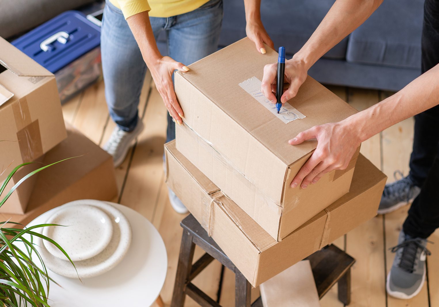 Close up of hand packing cardboard box, concept moving house. Young couple moving to a new apartment together. Relocation concept