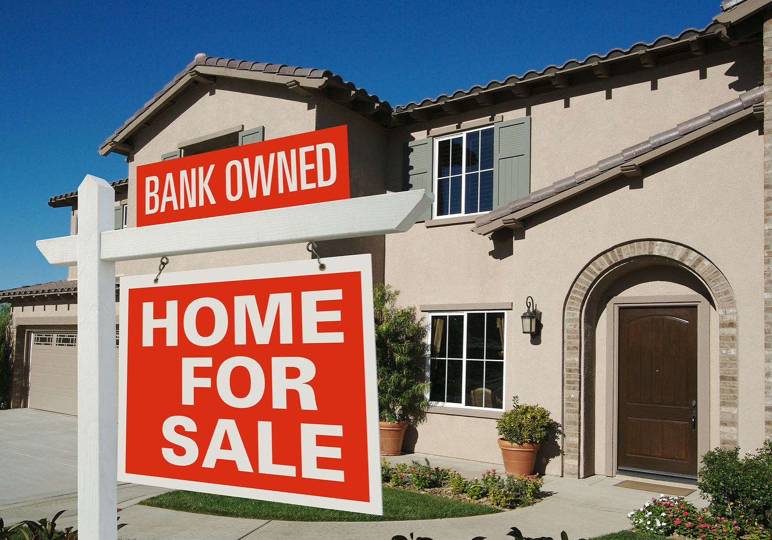 Bank Owned Home For Sale Sign in Front of New House on Deep Blue Sky